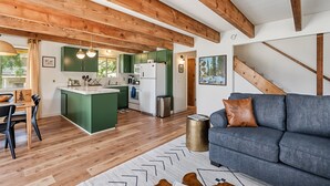 A modern kitchen with wooden beams, green cabinets, and a central island. - Marina Beach Cabin - Dog-Friendly Home with Deck! by Yosemite Region Resorts (Groveland)