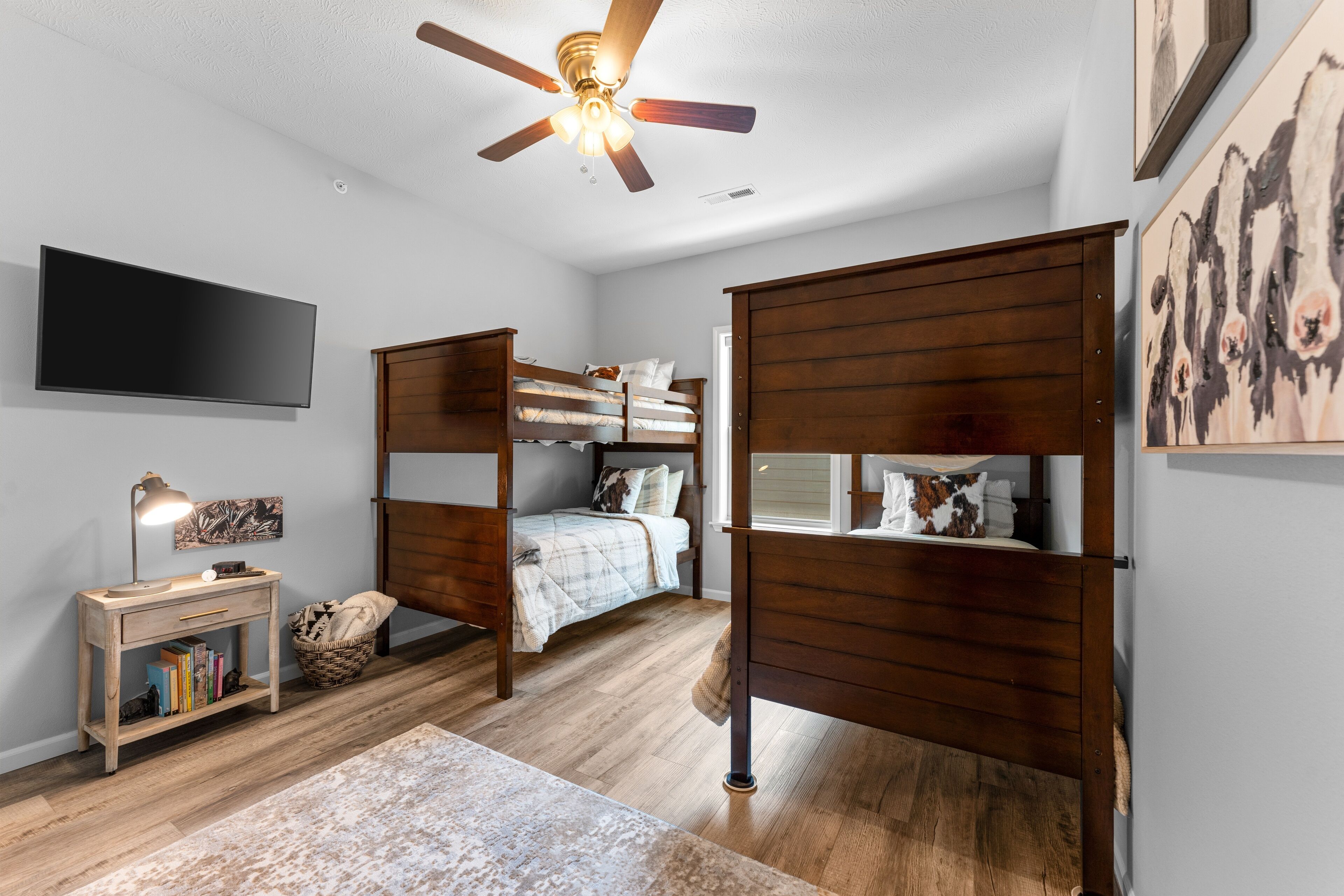 A bedroom with bunk beds, a desk, a TV, and artwork on the walls.