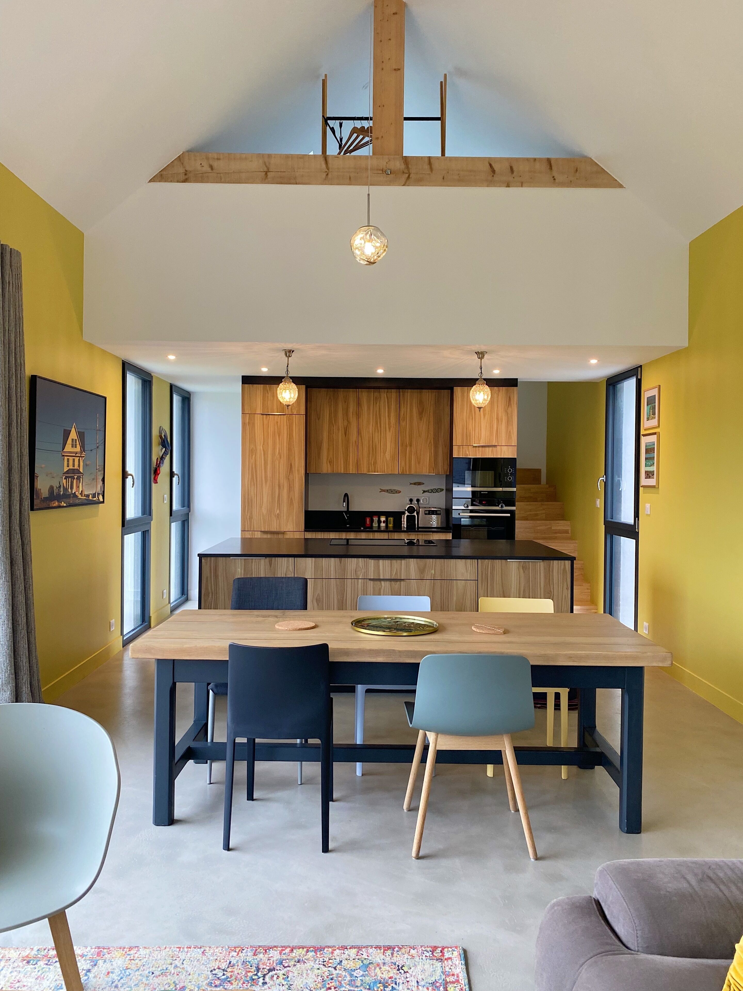 A modern kitchen with wooden cabinets, a central island, and pendant lighting.