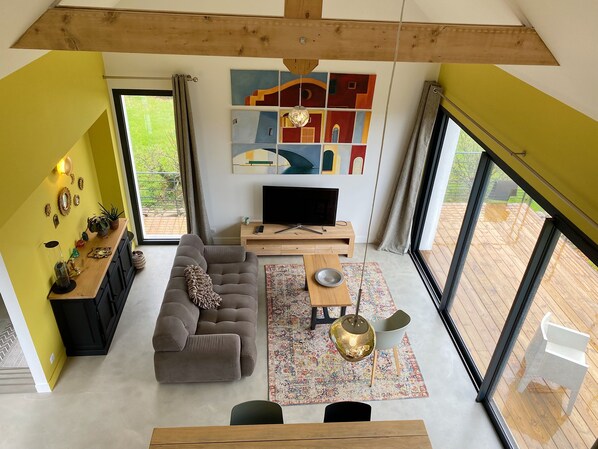 A modern living room with a sofa, TV, and artwork on the wall. - Beautiful Architect-Designed House, Kérity (Penmarc'h)