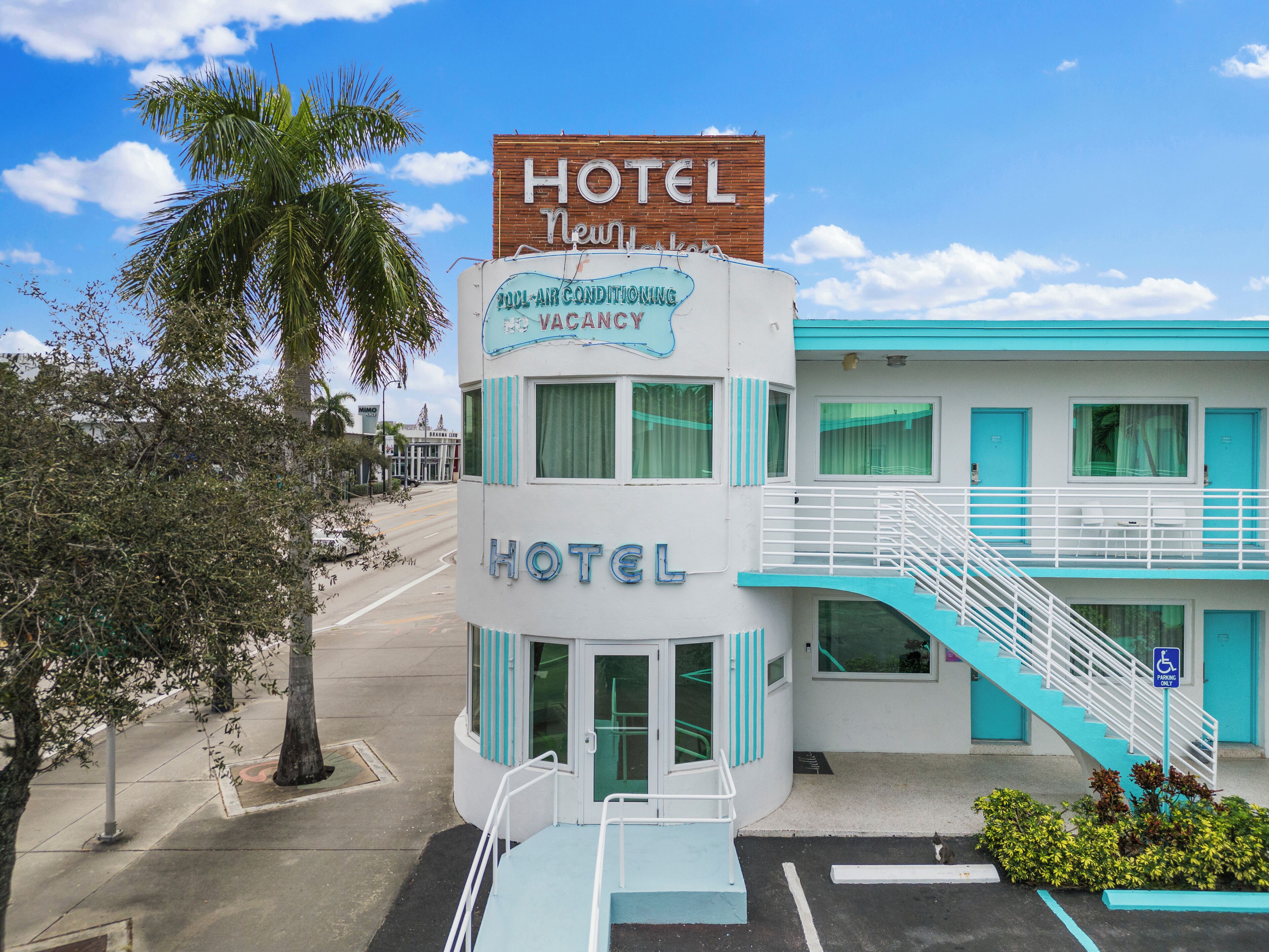 A hotel with a sign indicating a pool and air conditioning, a vacant room, and a staircase leading to an upper level.