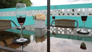 A glass table with two wine glasses and a vase with flowers.