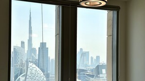 A room with a large window overlooking a cityscape with modern skyscrapers. - Lux BnB Amna Tower Burj Views (Dubai)