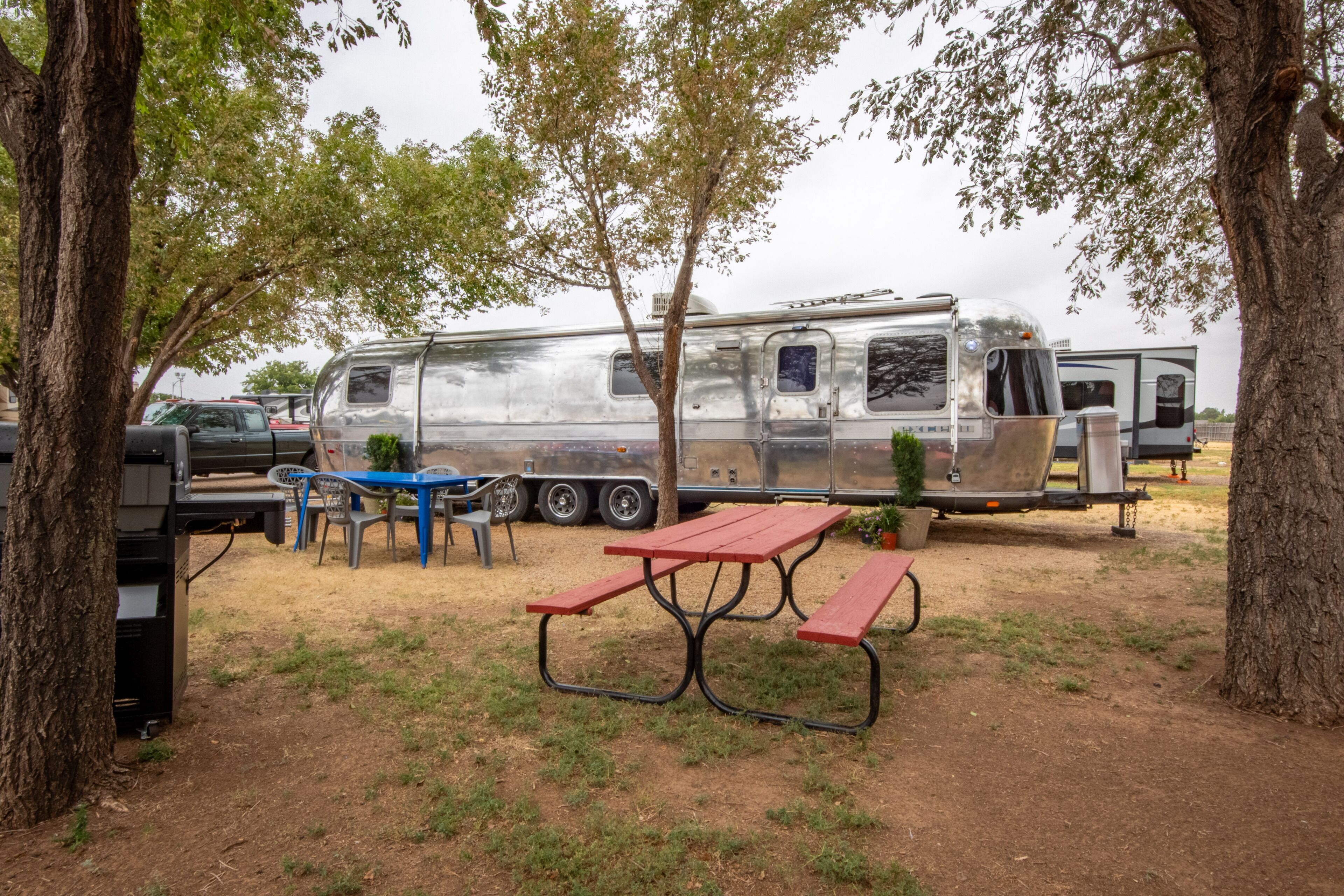 A campsite with a picnic table and chairs, a trailer, and a truck.