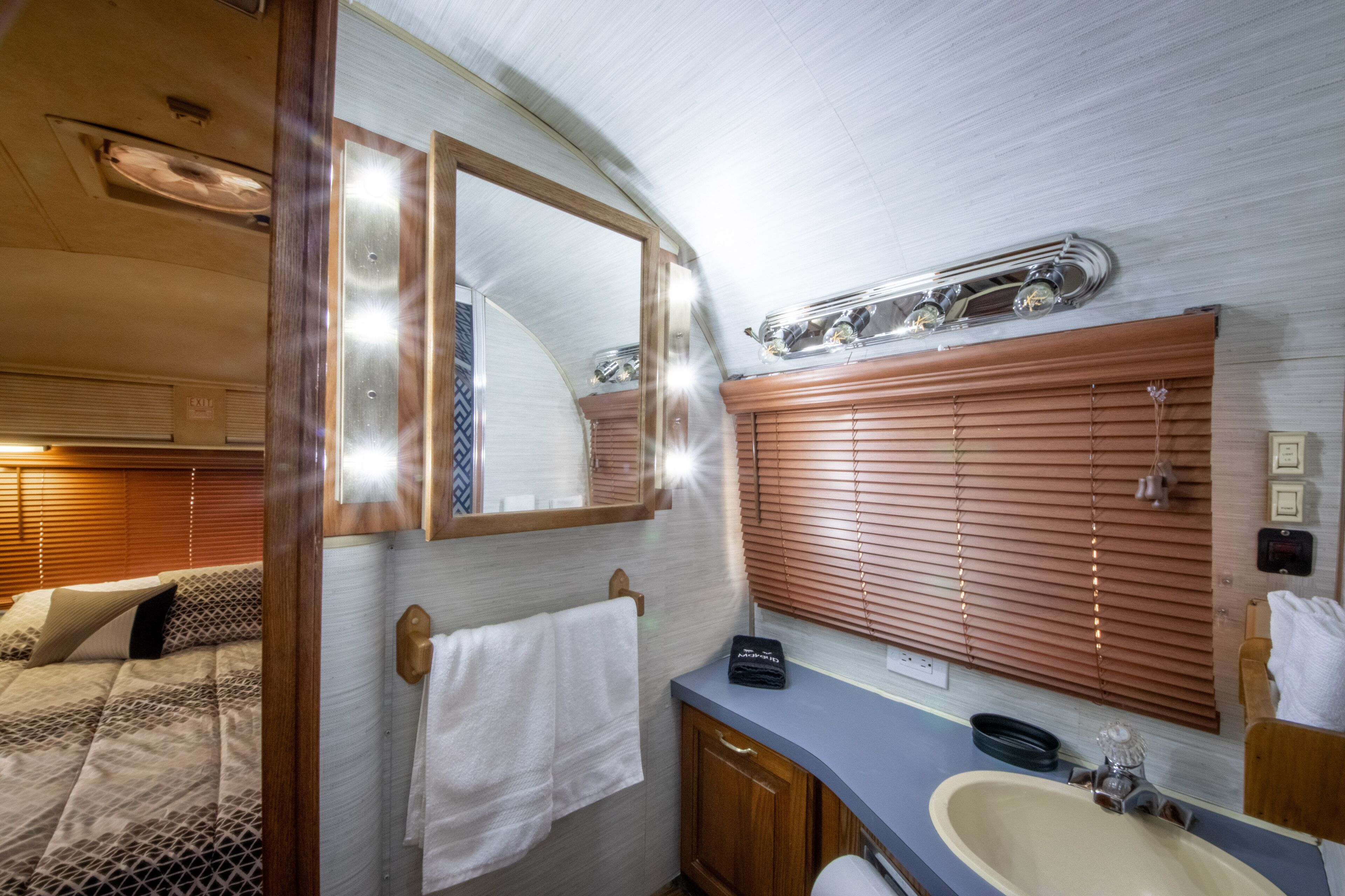 A compact bathroom with a wooden vanity, a sink, and a large mirror.