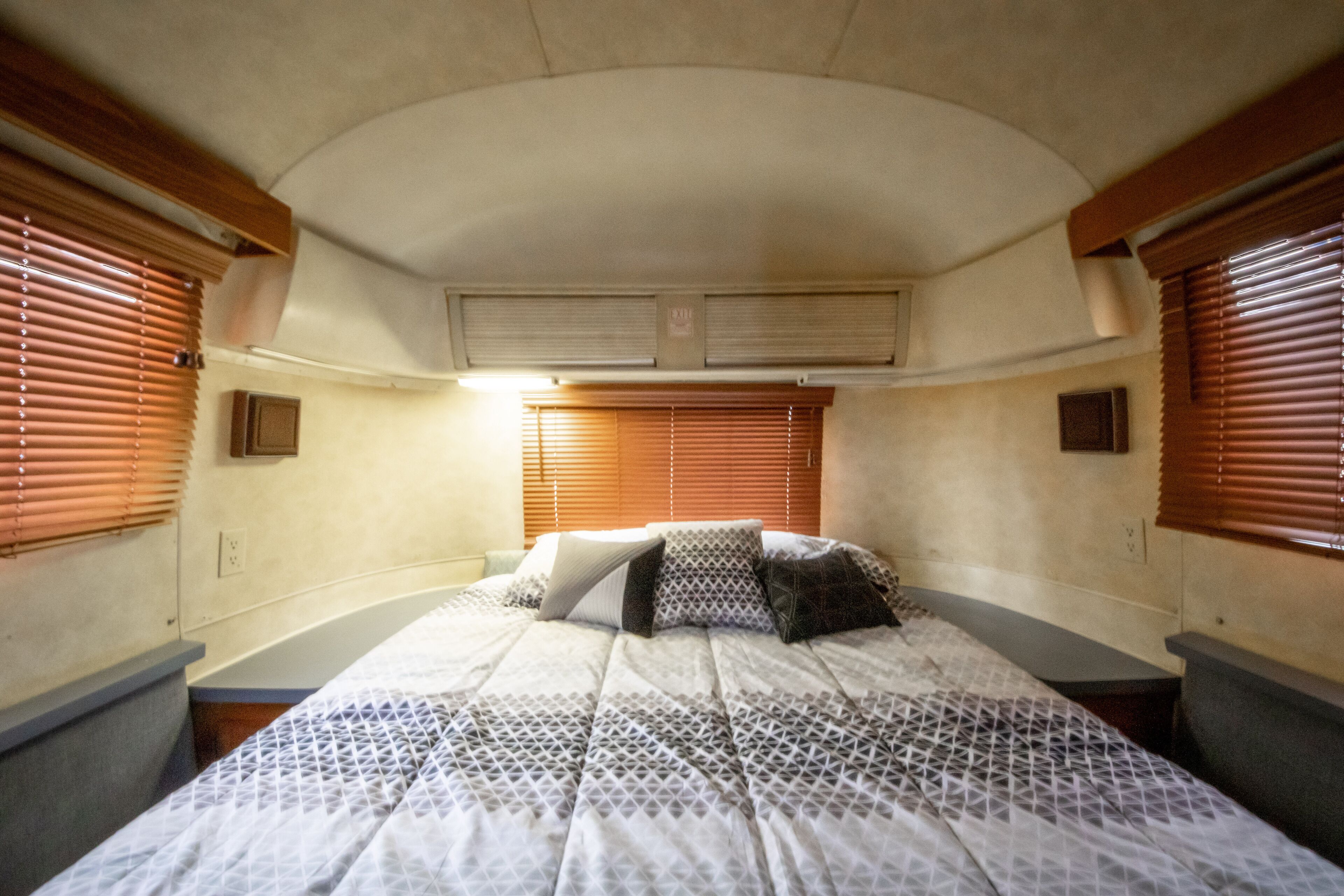 A bedroom with a bed, two bedside tables, and a window with blinds.