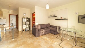 A modern living room with a sectional sofa, a glass dining table, and a TV mounted on the wall. - Nano's Vacation In Nea Skioni  (Kassandra)