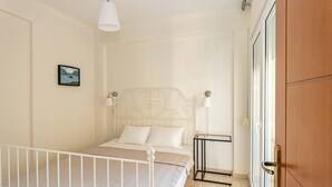 A bedroom with a bed, bedside tables, a nightstand, a door, and a wall-mounted picture. - Nano's Vacation In Nea Skioni  (Kassandra)