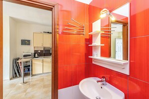 Um banheiro moderno com pia branca, espelho e paredes com azulejos vermelhos.