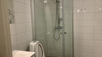 A modern bathroom with a glass-enclosed shower, a toilet, and a sink.
