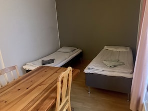 A small room with two single beds, a wooden table, and a chair. - Lovely 2-bed Apartment in Sundbyberg (Sundbyberg)