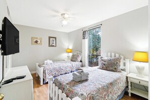 Relax in a spacious room with a single bed, bedside table, and ceiling fan, offering a comfortable stay with a view of the surrounding greenery.