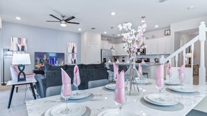A modern dining area with a marble table set for four, a ceiling fan, and a kitchen in the background. - Last Minute Disney Getaway! Private Pool & Themed Bedrooms. Book Now! #59697 (Orlando)