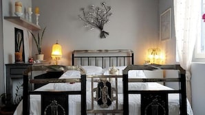 Un dormitorio con cama, lámparas de noche, un adorno en la pared y una ventana con cortinas.