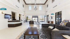 A spacious lobby with a reception desk, a Game Room, and a comfortable seating area with a sofa and a coffee table.