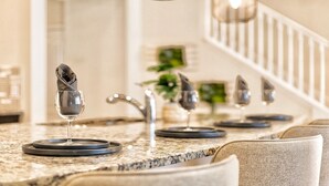 A kitchen counter with wine glasses and napkins.
