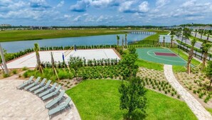 A sports court with a basketball court and a tennis court, surrounded by a grassy area with lounge chairs. - Last Minute Disney! Private Pool, Hot Tub, Game Room & Themed Bedrooms. Book Now! #57281 (Orlando)