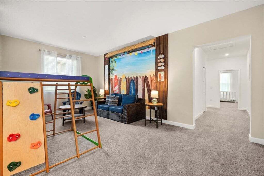 A playroom with a climbing wall, a sofa, and a mural.