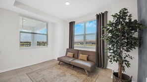 Relax in a spacious living room with a comfortable sofa, large window, and lush greenery.