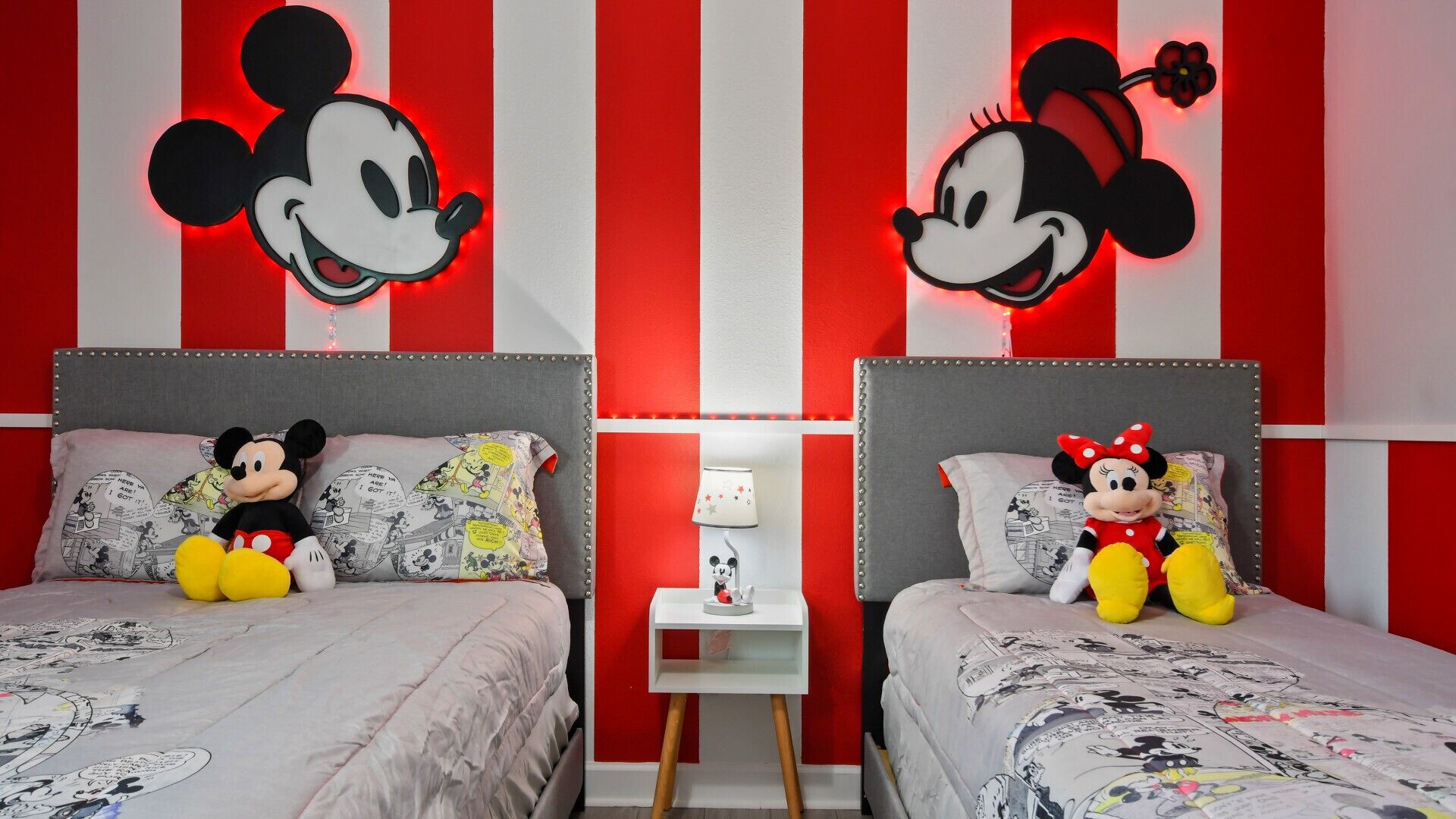 Une chambre avec deux lits, chacun doté d’une tête de lit et d’un oreiller décorés sur le thème de Mickey Mouse.