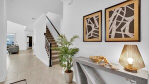 Ein modernes Interieur mit einer Treppe, einem Topfpflanzen und zwei abstrakten Kunstwerken an der Wand.
