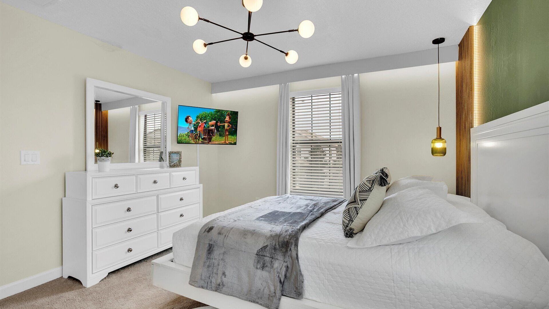 Een slaapkamer met een bed, een dressoir, een televisie en een plafondlamp.