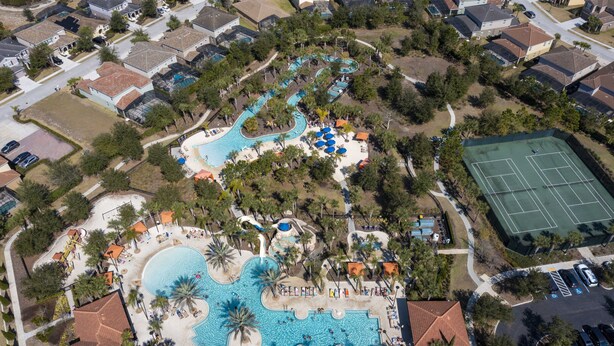 Eine Vogelperspektive eines Resorts mit einem großen Schwimmbad, Tennisplätzen und einem Wasserpark.
