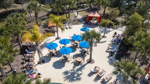 Eine Vogelperspektive eines Resorts mit Pool, Liegestühlen und Sonnenschirmen.