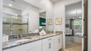 Un baño moderno con un espejo grande, dos lavamanos y una ducha.