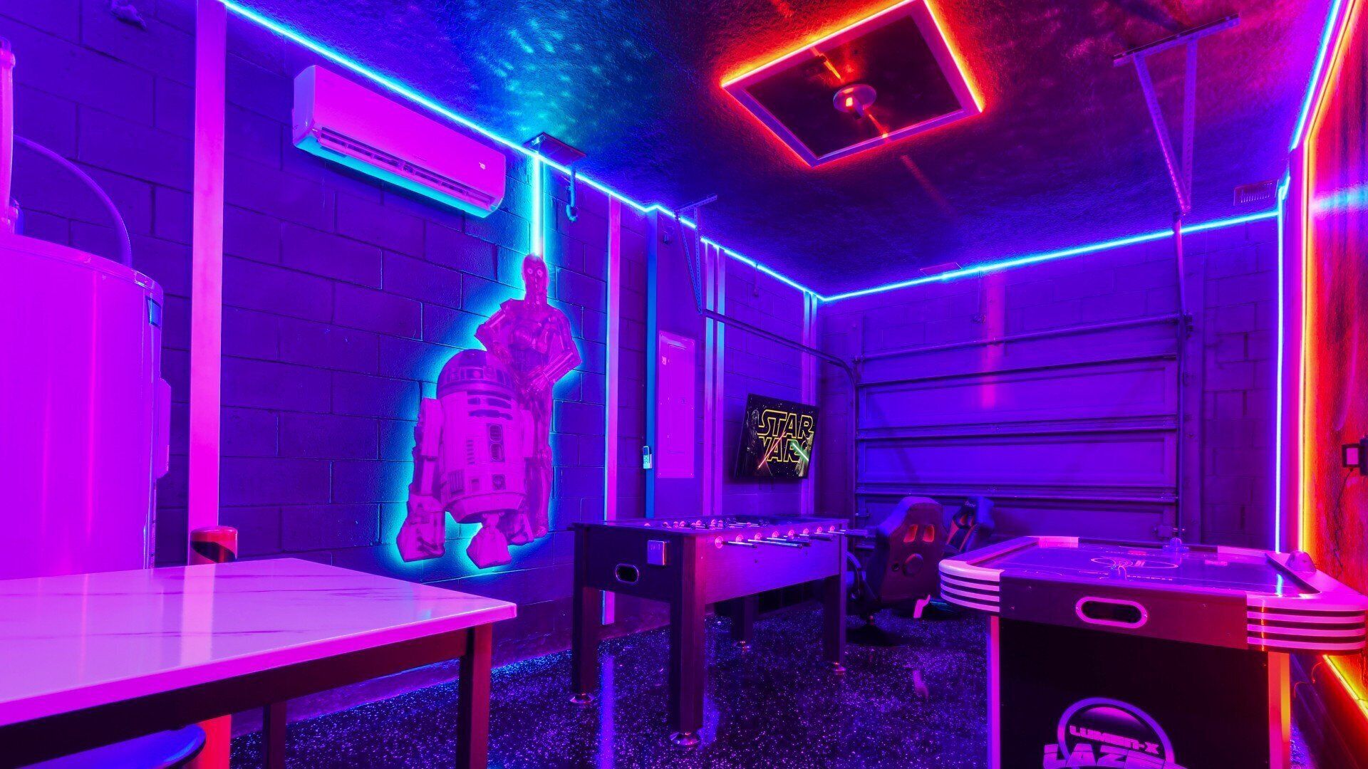 Een kamer met een Star Wars-thema, inclusief een R2-D2 figuur aan de wand, neonverlichting en een Star Wars bord.