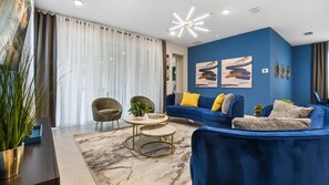 Un salon moderne avec un canapé bleu, une table basse ronde et une grande plante en pot.