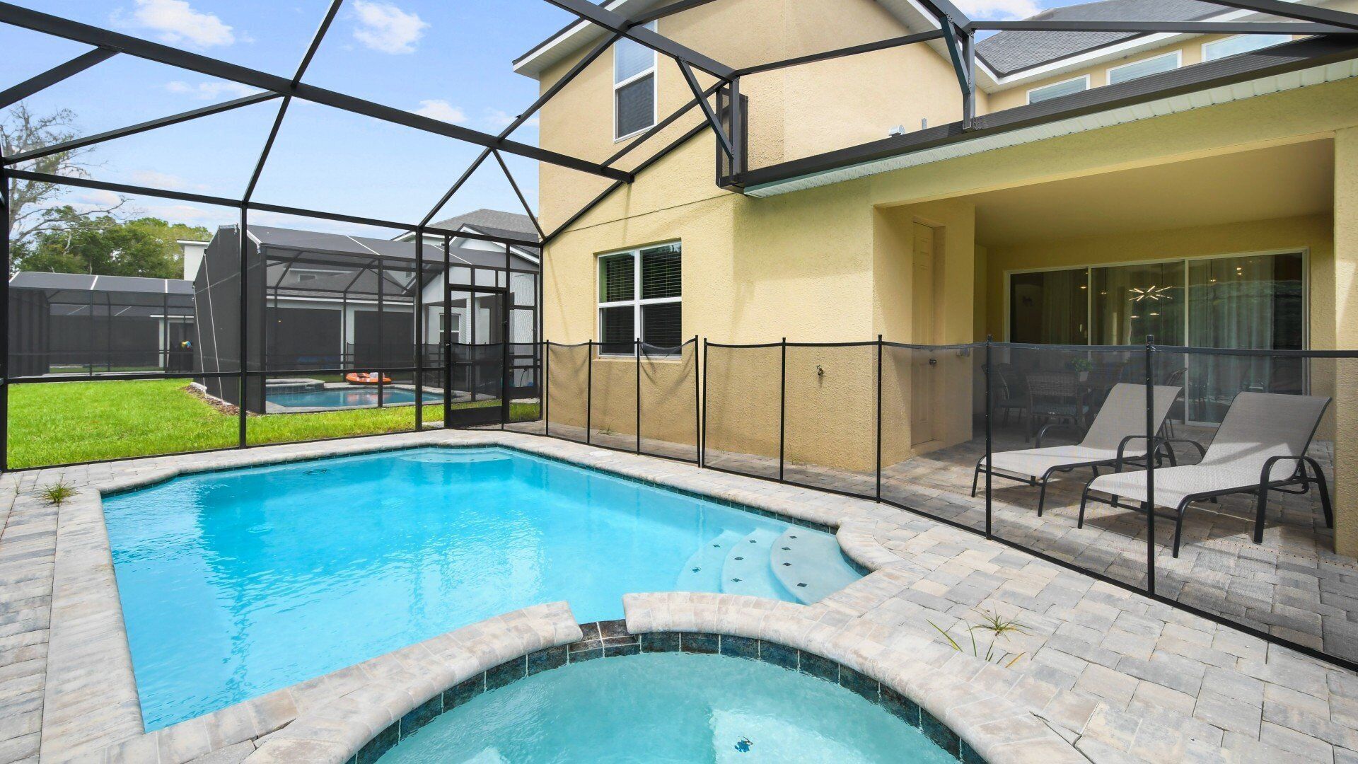 A swimming pool with a hot tub, surrounded by a covered patio area with outdoor furniture.