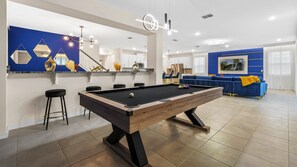 Enjoy a game of pool in this stylish living room with a pool table and comfortable seating.