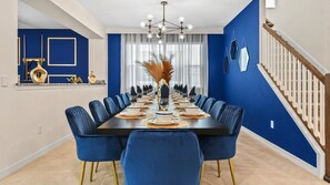 Enjoy meals in this dining area with a long table and modern chandelier.