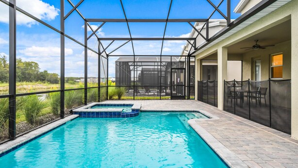 A swimming pool with a hot tub, surrounded by a covered patio area with a view of the landscape. - Last Minute Disney! Private Pool, Hot Tub & Themed Bedrooms. Book Now! #79721 (Orlando)
