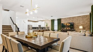 A modern living room with a dining area, a kitchen in the background, and a staircase. - Last Minute Disney! Private Pool, Hot Tub & Themed Bedrooms. Book Now! #79721 (Orlando)