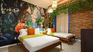 Huoneessa on kaksi sänkyä, seinällä suuri viidakkomaisemaa esittävä seinämaalaus, puinen seinä ja roikkuvia kasveja.