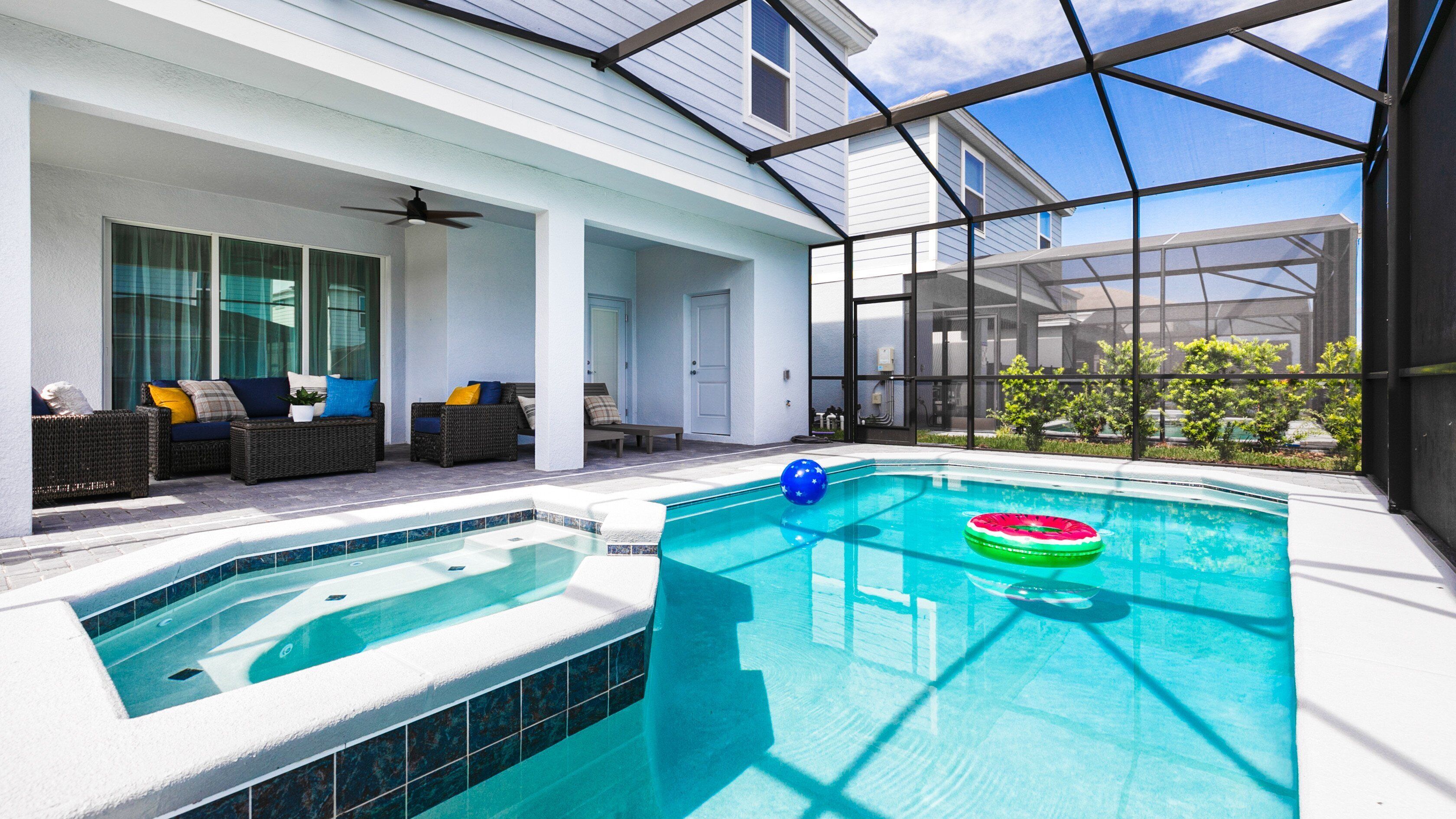 Ein Schwimmbecken mit Whirlpool, Außenbereich zum Sitzen und einer überdachten Terrasse.