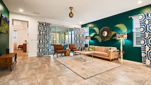 Uma sala de estar moderna com um sofá bege, duas poltronas, uma mesa de centro e um tapete estampado.