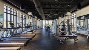 Un gimnasio con cintas de correr, máquinas de pesas y espejos en las paredes.