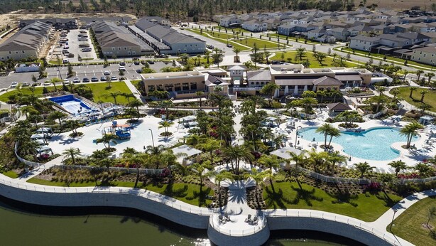 Vista aérea de un complejo turístico con piscina central, varias construcciones y una carretera circundante.