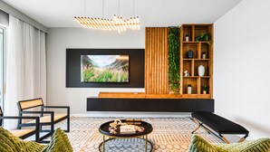 Una sala de estar moderna con un televisor de pantalla plana grande, una mesa consola de madera, un sofá negro y una alfombra estampada.