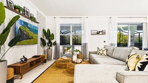 A modern living room with a large flat-screen TV, a sofa, a coffee table, and a bookshelf. - Last Minute Disney! Private Pool, Hot Tub, Game Room & Themed Bedrooms. Book Now! #81847 (Orlando)
