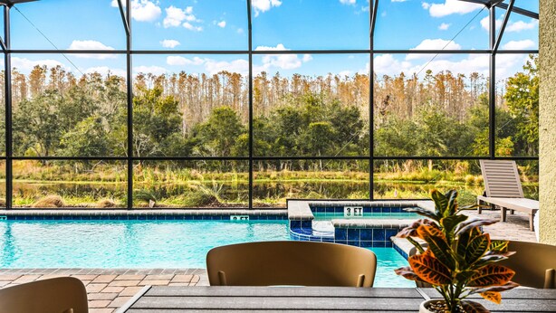 A pool area with a view of a forest through large windows. - Last Minute Disney! Private Pool, Hot Tub, Game Room & Themed Bedrooms. Book Now! #81847 (Orlando)