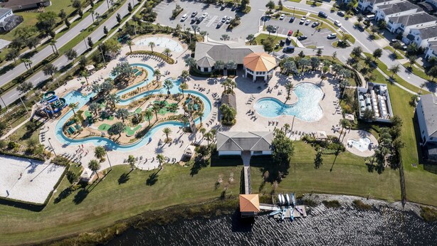 Vista aérea de un resort con un área de piscina central, varias piscinas y un tobogán de agua grande.