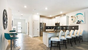 A modern kitchen with white cabinets, stainless steel appliances, and a central island with bar stools. - Last Minute Disney! Private Pool, Hot Tub, Game Room & Themed Bedrooms. Book Now! #87159 (Orlando)
