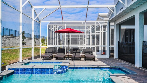 A pool area with a glass-enclosed patio, outdoor seating, and a red umbrella. - Last Minute Disney! Private Pool, Hot Tub, Game Room & Themed Bedrooms. Book Now! #87159 (Orlando)