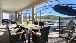 Ein überdachter Patio mit Pool, Gartenmöbeln und Blick auf die Landschaft.