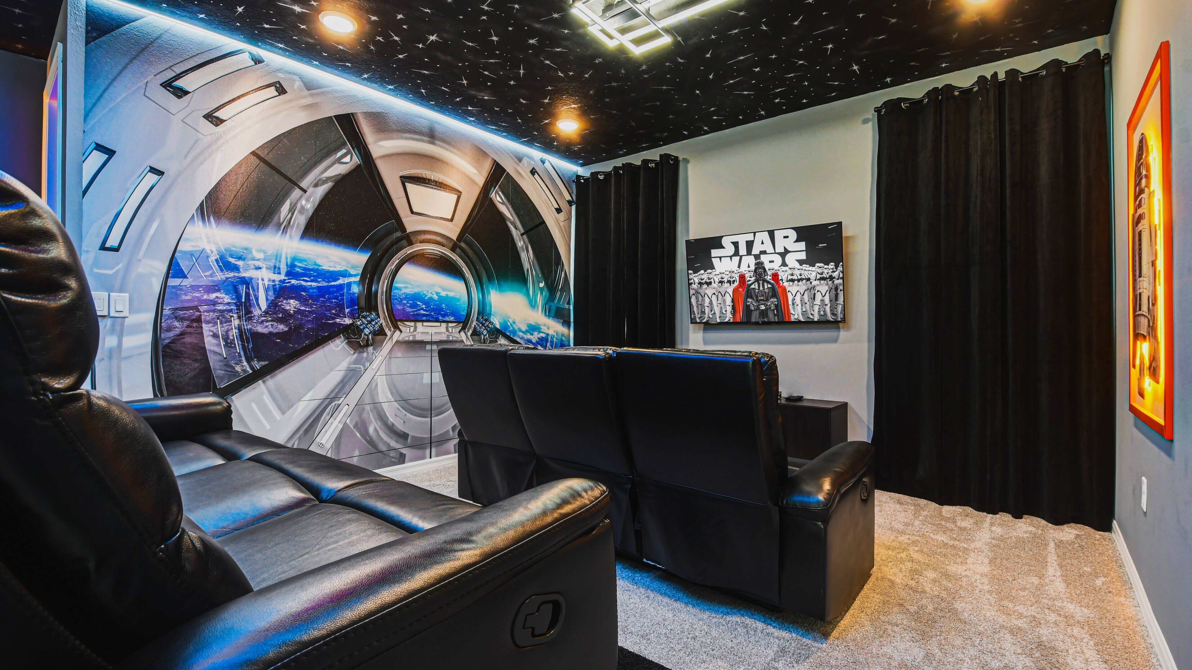 Ein Heimkino mit einer gebogenen Leinwand, schwarzen Ledersesseln und einer Dekoration im Stil von Star Wars.