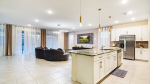 Una cocina moderna con una isla central, electrodomésticos de acero inoxidable e iluminación colgante.